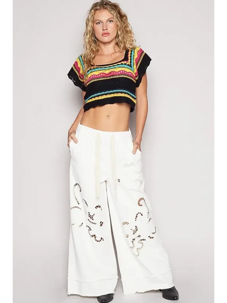 POL  boho knit beach top in multi-color worn with white wide-leg pants by a female model