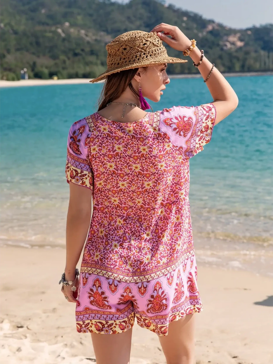Babe Beachwear colorful floral short sleeve romper worn by woman on beach with straw hat