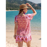 Babe Beachwear colorful floral short sleeve romper worn by woman on beach with straw hat