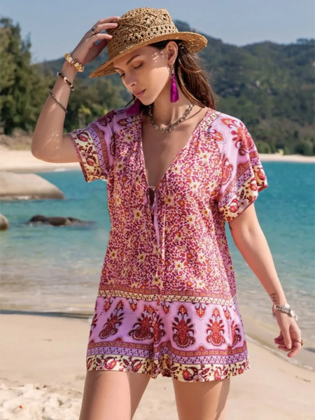Babe Beachwear short sleeve romper with pink and red floral print worn by woman on beach