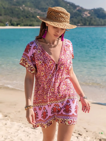 Babe Beachwear short sleeve romper with pink floral pattern worn with straw hat on the beach