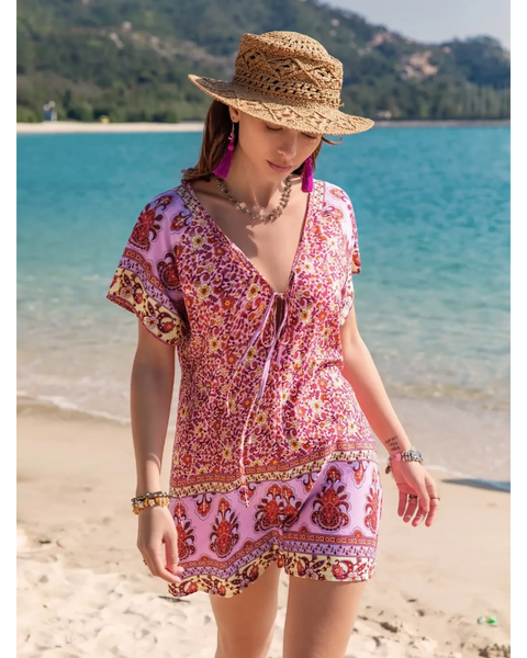 Babe Beachwear short sleeve romper with pink floral pattern worn with straw hat on the beach