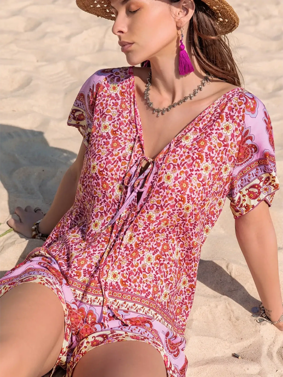 Babe Beachwear short sleeve romper with pink floral pattern worn on sand beach