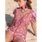 Babe Beachwear short sleeve romper with pink floral pattern worn on sand beach