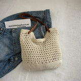 Braided tote bag with leather straps by Babe Beachwear placed on denim jeans and white surface