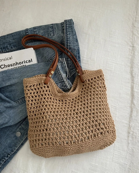 Babe Beachwaer braided tote bag with leather straps placed on denim jacket and white surface