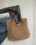 Babe Beachwaer braided tote bag with leather straps placed on denim jacket and white surface