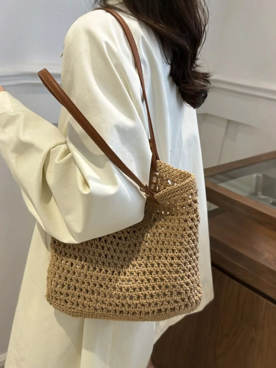 Braided tote bag with leather straps worn over shoulder with white long sleeve shirt