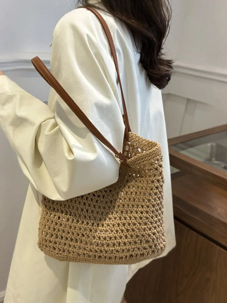 Braided tote bag with leather straps worn over shoulder with white long sleeve shirt