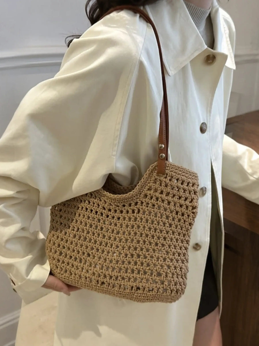 Braided tote bag with leather straps worn over shoulder by person in cream coat