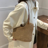 Braided tote bag with leather straps worn over shoulder by person in cream coat