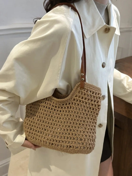 Braided tote bag with leather straps worn over shoulder by person in cream coat