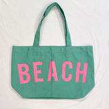 Babe Beachwear Canvas Beach Tote in green with large pink BEACH lettering and shoulder straps