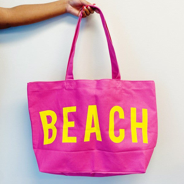 Bright pink Canvas Beach Tote from Babe Beachwear with bold yellow beach text and long handles