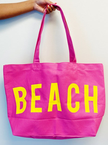 Bright pink Canvas Beach Tote from Babe Beachwear with bold yellow beach text and long handles