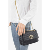 CG Logo Quilted Shoulder Bag in black with gold chain strap worn with white shirt and blue jeans