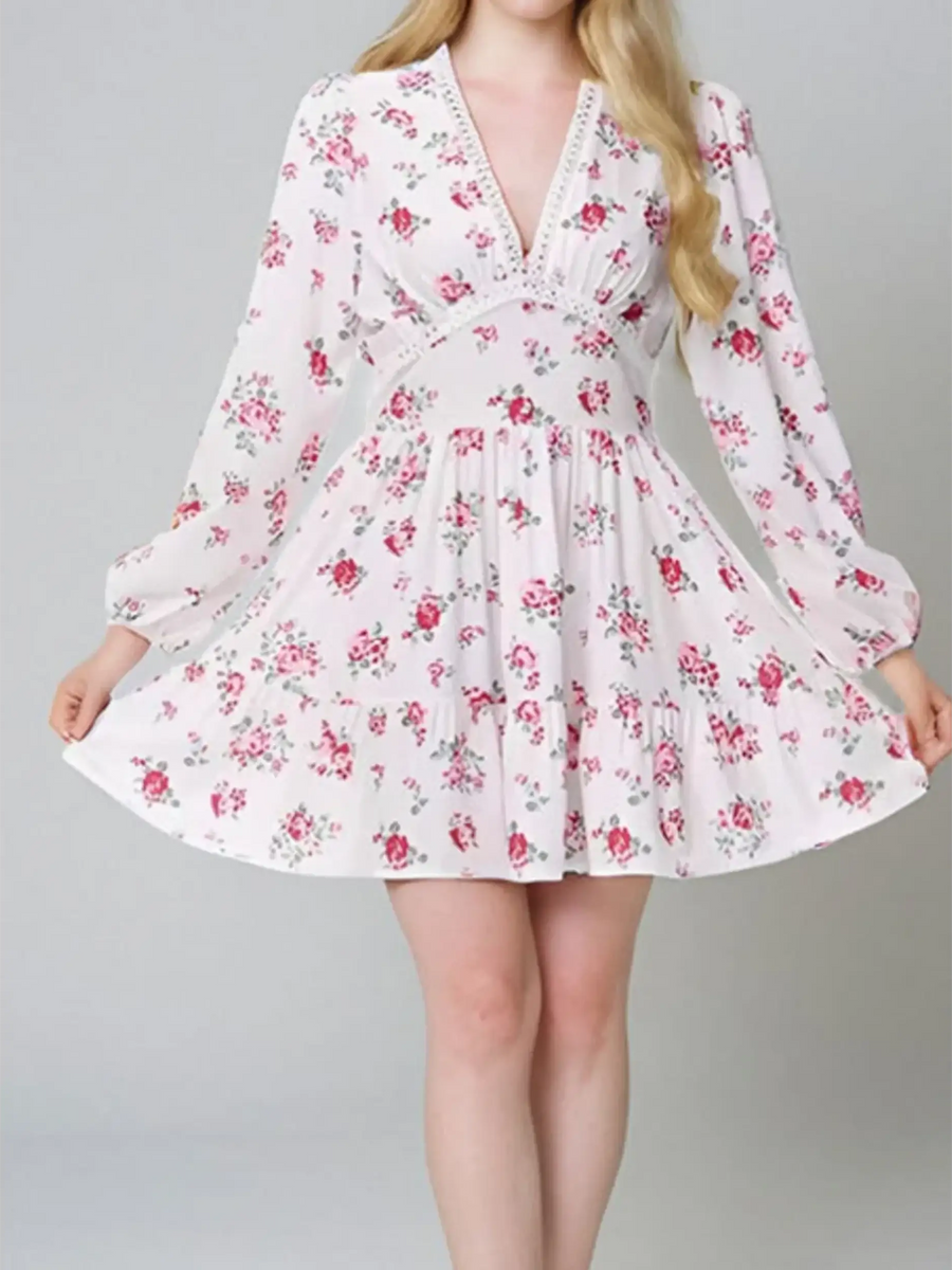 Woman showing detail ofi white floral mini dress with long sleeves and v-neck perfect for chic beachwear dresses for curvy women