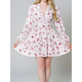 Woman showing detail ofi white floral mini dress with long sleeves and v-neck perfect for chic beachwear dresses for curvy women