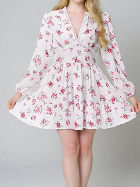 Woman showing detail ofi white floral mini dress with long sleeves and v-neck perfect for chic beachwear dresses for curvy women