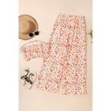 Trendsi chic boho beachwear set with floral print pants and matching top laid flat with hat and sunglasses