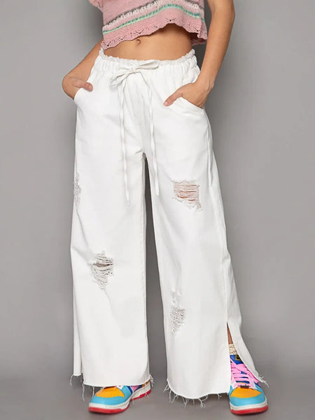 Ripped white cotton beach pants for a fashion forward summer look in wide leg beach pants