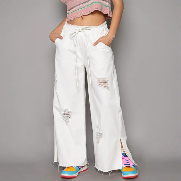 Ripped white cotton beach pants for a fashion forward summer look in wide leg beach pants