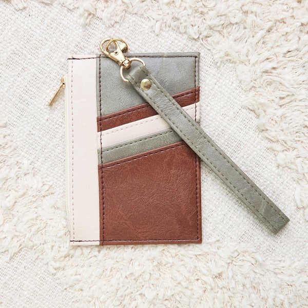 Babe Beachwear Compact Wrist Wallet and Card Case in brown, gray, and cream with wrist strap on textured fabric background