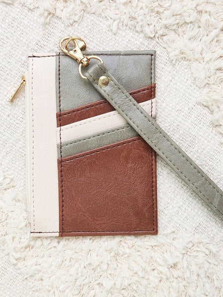 Babe Beachwear Compact Wrist Wallet and Card Case in brown, gray, and cream with wrist strap on textured fabric background