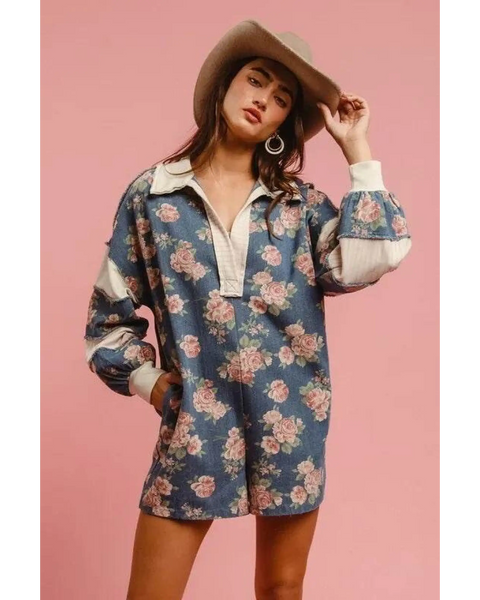 Woman wearing a Babe Beachwear contrast collar summer romper with floral print and long sleeves worn with a hat
