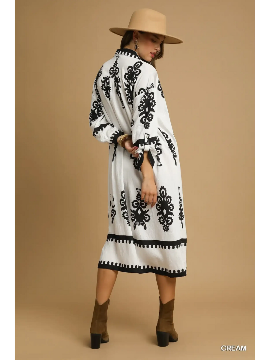 Trendsi long sleeve resort tunic dress in cream with black patterns worn with tan hat and brown ankle boots