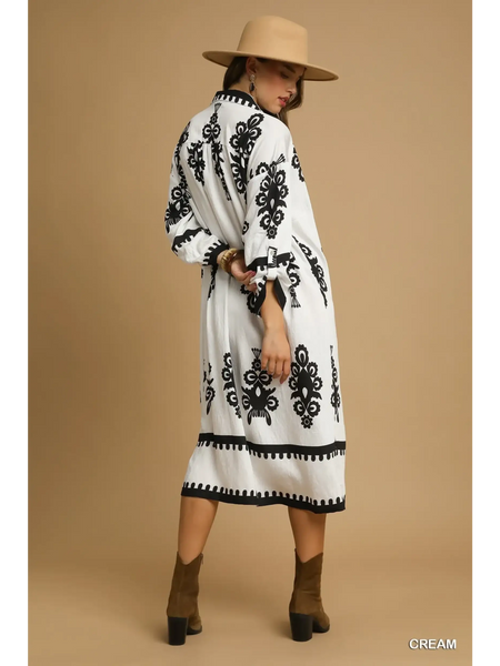 Trendsi long sleeve resort tunic dress in cream with black patterns worn with tan hat and brown ankle boots