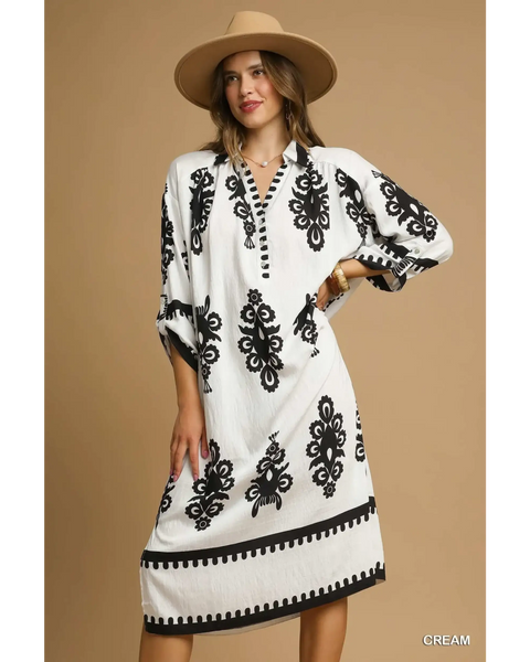  long sleeve resort tunic dress in cream with black floral patterns and buttoned neckline