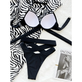Beach Babes crisscross halter neck bikini in black laid flat on zebra print fabric