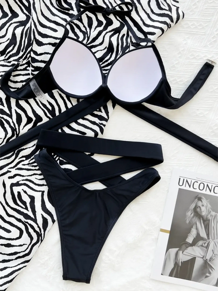 Beach Babes crisscross halter neck bikini in black laid flat on zebra print fabric