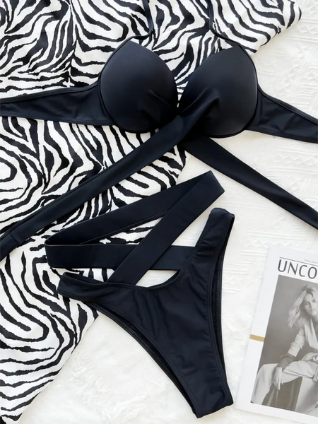 Beach Babes black crisscross halter neck bikini laid on zebra print fabric with a fashion magazine nearby