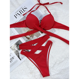 Beach Babes red crisscross halter neck bikini laid flat on white textured surface with magazine background
