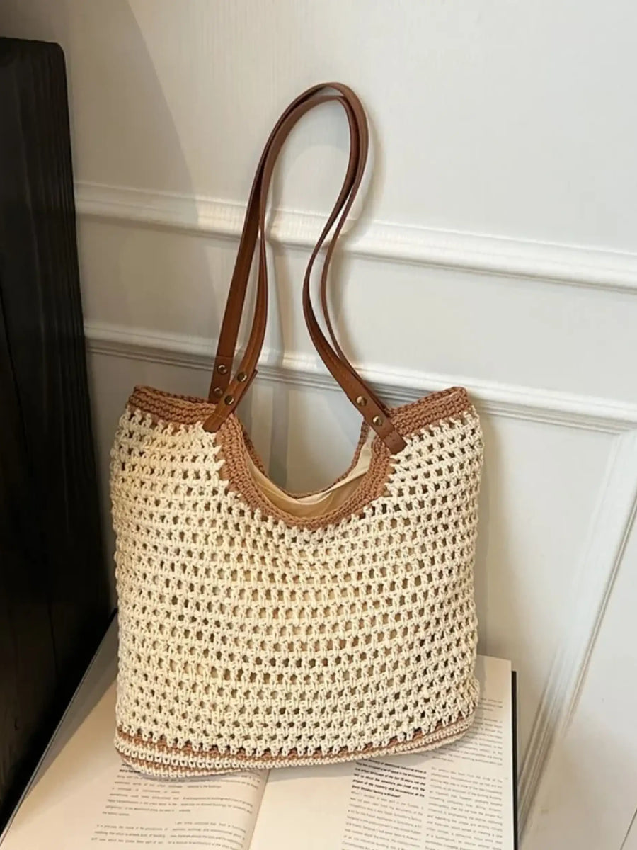 crochet tote bag with leather handles in cream and brown colors on a white surface