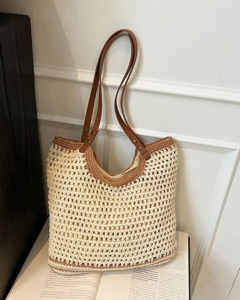 crochet tote bag with leather handles in cream and brown colors on a white surface
