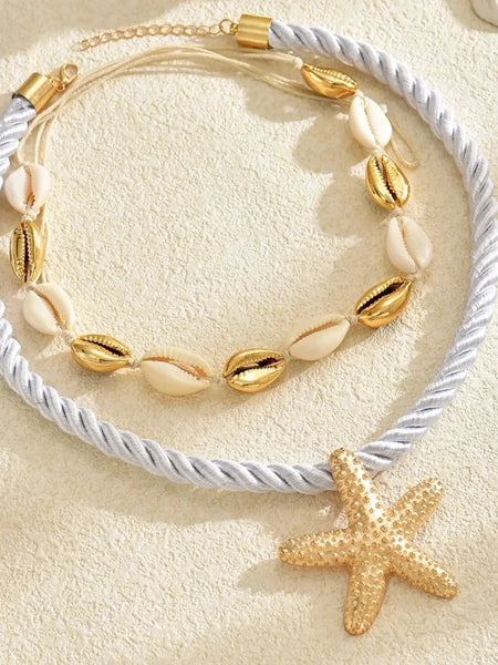 Trendsi cruise wear beaded rope necklace with gold starfish pendant and shell beads on sandy background
