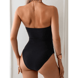 Back view of a black cutout one piece swimsuit by Beach Babes worn by a model with bracelet accessory