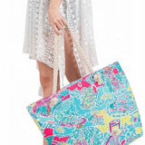 Babe Beachwear easy to pack summer beach bag with colorful tropical print carried by woman in white dress