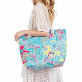Babe Beachwear colorful easy to pack summer beach bag with tropical print worn by woman in white dress