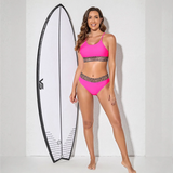 Trendsi fierce pink bikini for beach with leopard print trim modeled next to a surfboard