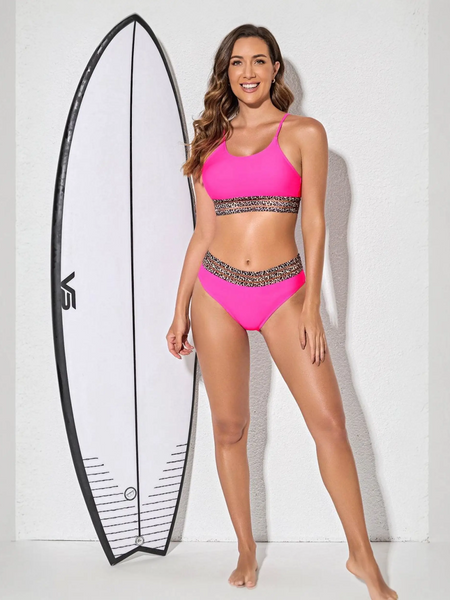 Trendsi fierce pink bikini for beach with leopard print trim modeled next to a surfboard