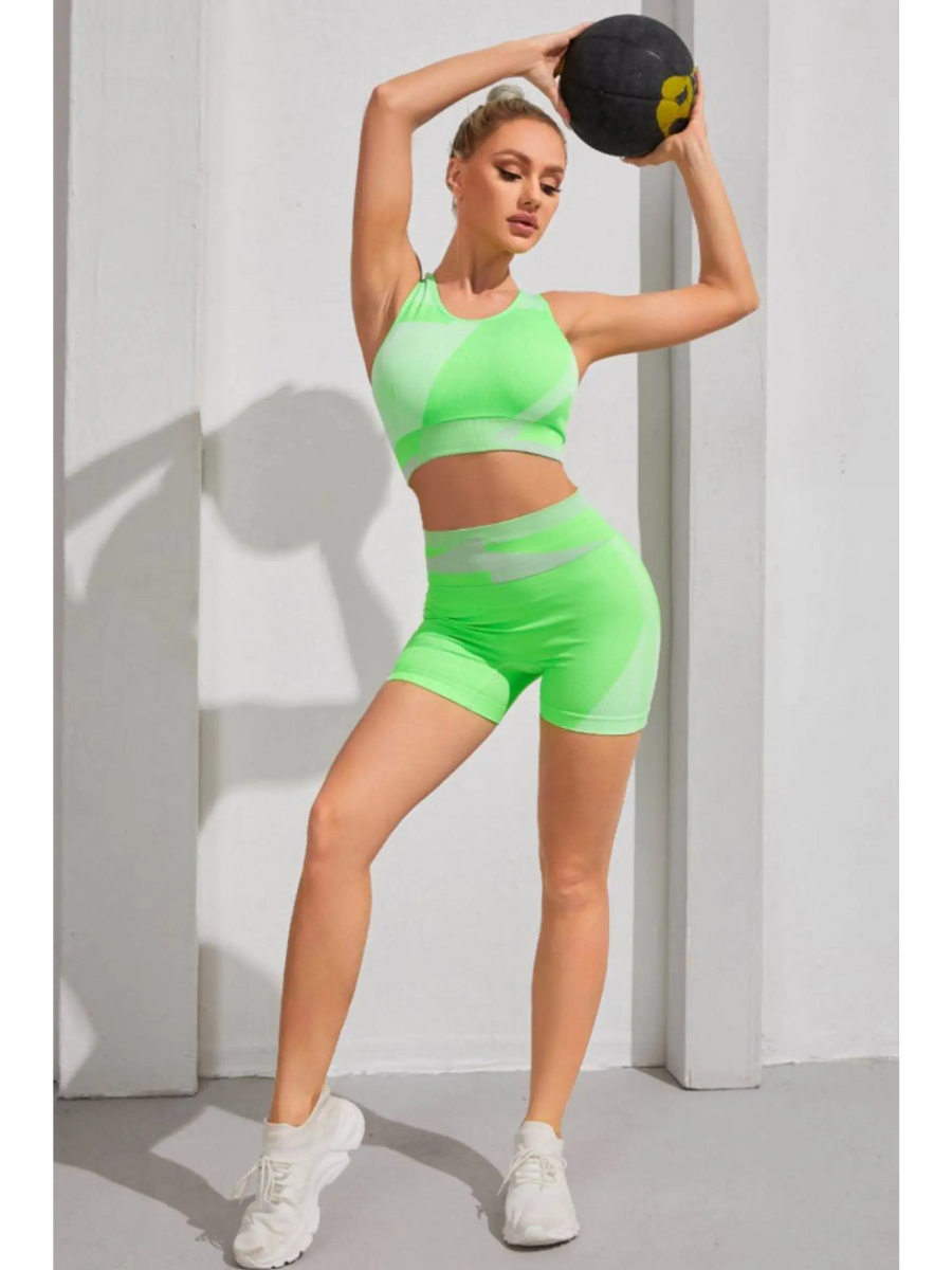 Babe Beachwaer color block sports bra and shorts set in green worn by woman holding a medicine ball