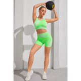 Babe Beachwaer color block sports bra and shorts set in green worn by woman holding a medicine ball