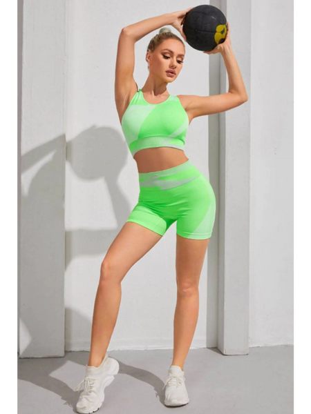 Babe Beachwaer color block sports bra and shorts set in green worn by woman holding a medicine ball