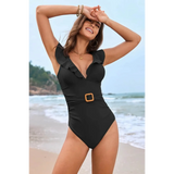 Babe Beachwear flattering one piece swimwear in black with ruffle details and belt on beach
