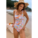 Beach Babes floral one piece swimsuit with colorful flowers worn by woman at the beach