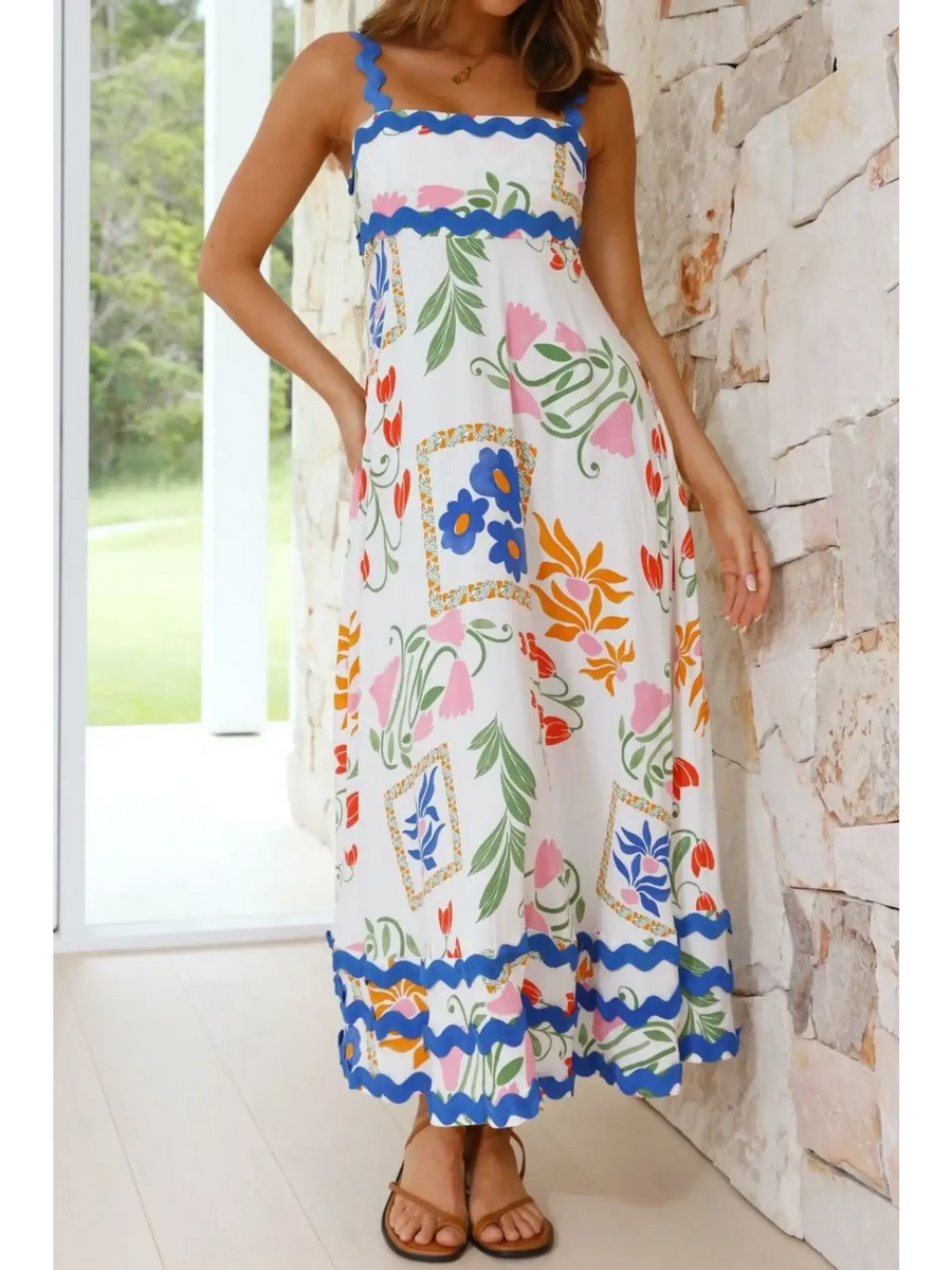woman wearing floral resort wear dress with colorful floral patterns and blue trim maxi dress